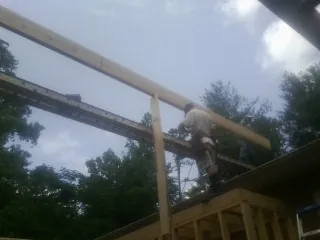 Carpenter setting a ridge beam over a new addition frame — Ice Dam Removal by Roofing Brothers in Nesmith