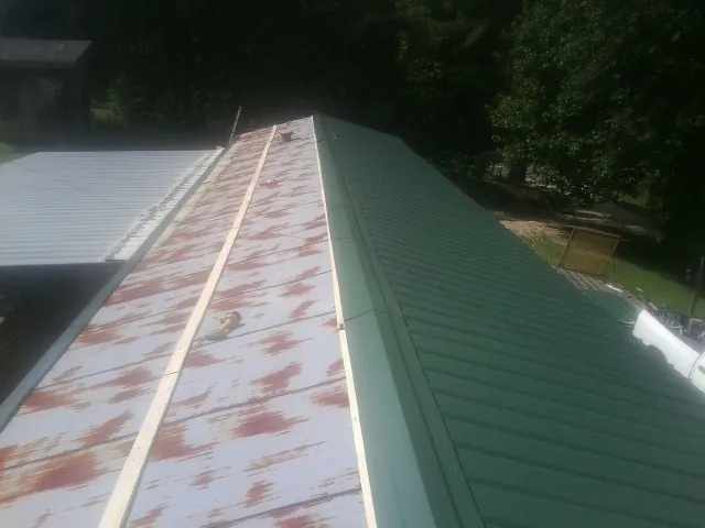 Old rusted panels beside newly installed green metal roofing — Wind Damage Roof Repair by Roofing Brothers in Nesmith