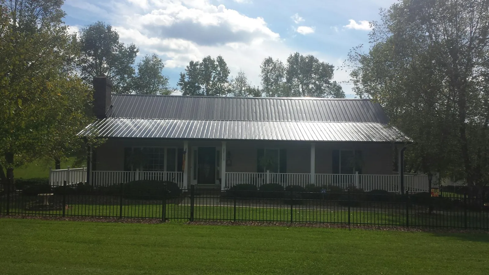 Gray metal roof on a brick ranch with a full width front porch — Gutter Guard Installation work by our crew in Nesmith