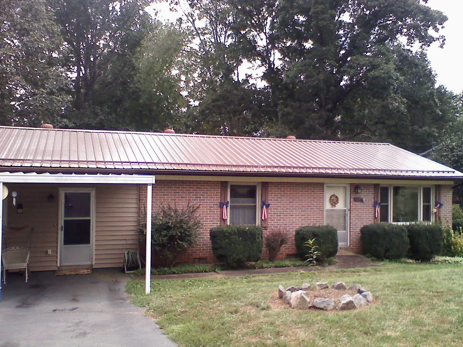 Bronze metal roof and carport on a brick ranch home — Roof Repair work by our crew in Nesmith